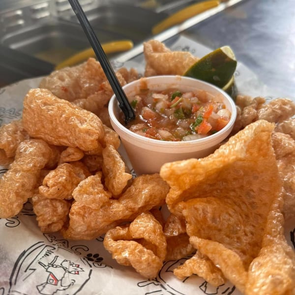 Crispy chicharrones with a side of fresh salsa and a lime wedge from Pacos Tacos.