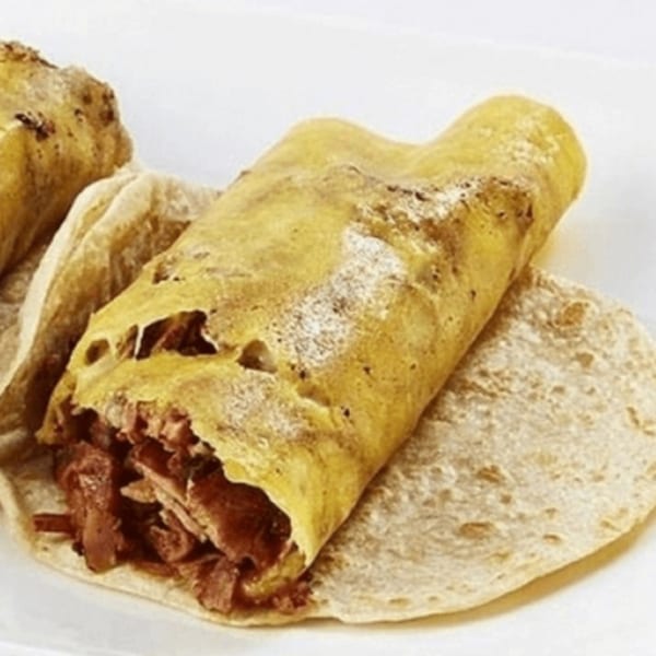 A close-up of a Pacos Tacos taco with a golden-brown tortilla and savory meat filling.