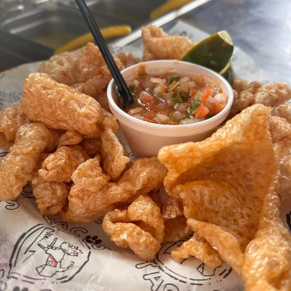 Paco's Tacos chicharrones with a side of fresh salsa and a lime wedge.